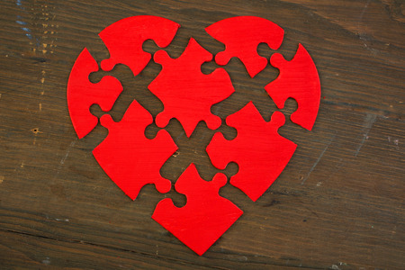 Red puzzle heart with all pieces separate on wooden backgroundの写真素材