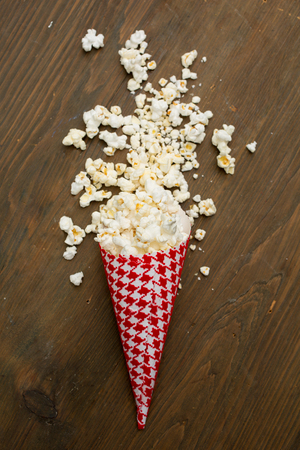 Top view of a red container full of fresh popcorn on a wooden tableの写真素材