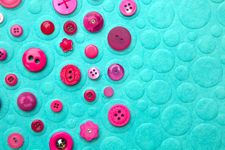 Collection of 2 and 4 holes pink buttons on a turquoise background with textureの写真素材