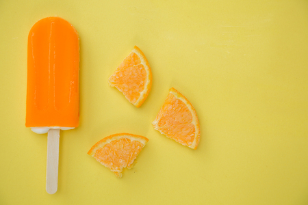 orange ice cream with few slice of orange on a yellow backgroundの写真素材