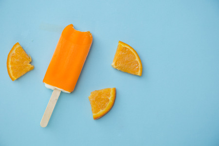 orange ice cream with few slice of orange on a blue backgroundの写真素材