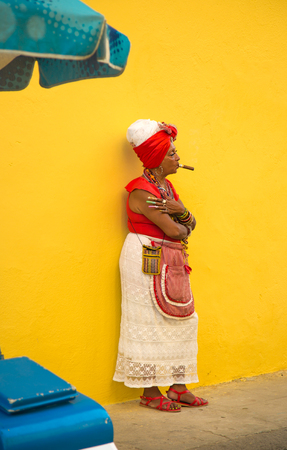 HAVANA-CUBA- DEC 4, 2018:  Cuban cigar smoking woman agains a yellow wallのeditorial素材