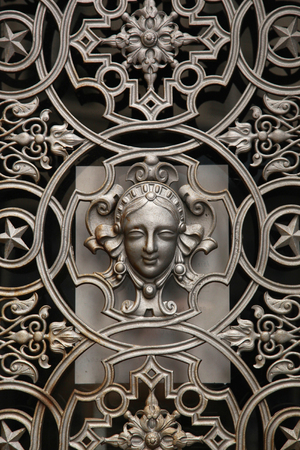 Parisian decorative metal door window in silver colour with a face in the middleの写真素材