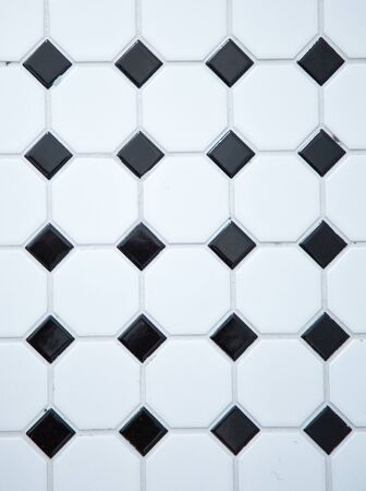 Vertical picture of a white and black  mat tiles on a wall with grey cementの写真素材
