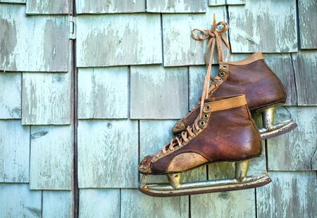 Vintage masculine leather ice skate  hanging on a green mint grunge wallの写真素材