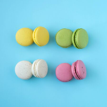 Top view of colorful french traditional macarons in yellow, green, white and pink on blue backgroundの写真素材