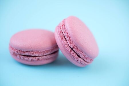 Two french traditional pink macarons on pastel blue backgroundの写真素材