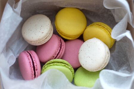 Colourful traditional macarons offered in a box and paperの写真素材