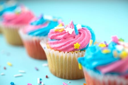 Cupcakes with blue and pink icing on a blue backgroundの写真素材