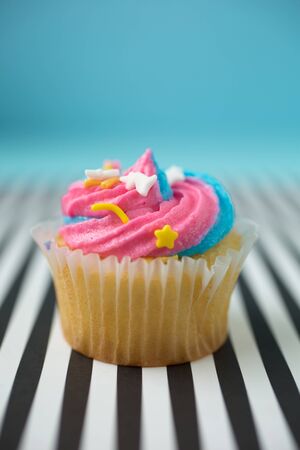 Cupcake with blue and pink icing on a black and white lined backgroundの写真素材