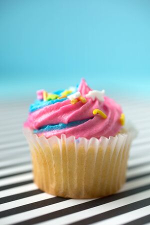 Cupcake with blue and pink icing on a black and white lined backgroundの写真素材