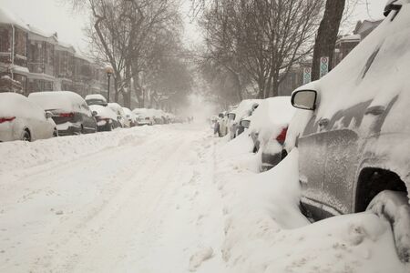 Car covered of snow and parked in a street during a snowstorm in Montreal in  Canadaの写真素材