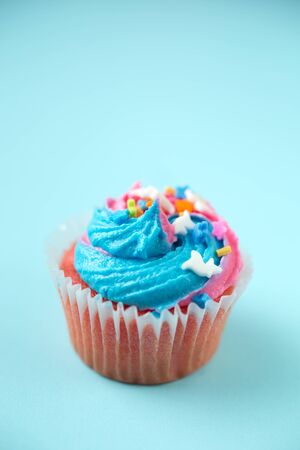 Cupcakes with blue and pink icing on a blue backgroundの写真素材