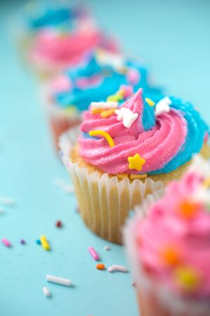 Cupcakes with blue and pink icing on a blue backgroundの写真素材