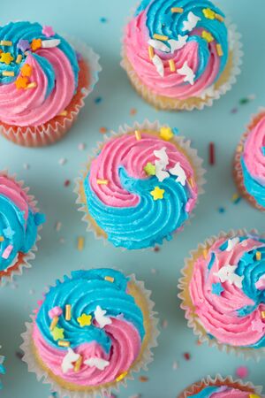 Top view of cupcakes with blue and pink icing on a blueの写真素材