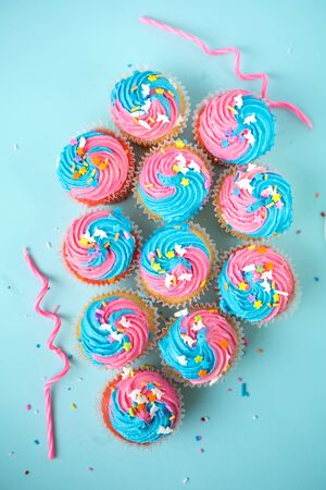 Top view of cupcakes with candles and  blue and pink icing on a blueの写真素材
