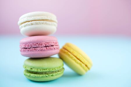Pink, yellow, white and green traditional french macaroons on pink and blueの写真素材
