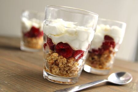Delicious plain yogurt with nuts and a berry coulis in a jar on a wooden backgroundの写真素材