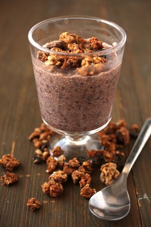 Healthy chocolate chia pudding with fresh nuts in a glass jar and spoon on a woodenの写真素材