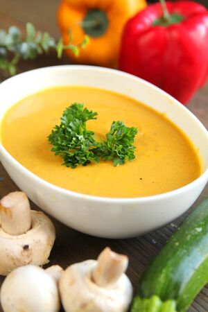 Vegetables soup with fresh mushrooms, zucchini and capsicum on a wooden backgroundの写真素材