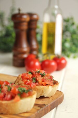 Close up of roasted brushetta with olive oil, garlic and fresh basil and fresh pepper in the backgroundの写真素材