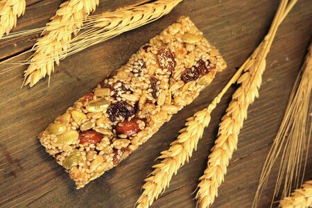 Top view of a granola bar with honey, almond, nuts, raisin and wheat on a wooden tableの写真素材