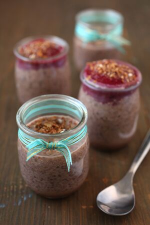 Healthy chocolate chia pudding with berry coulis on top with nuts and spoon on a woodenの写真素材