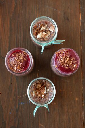 Top view of healthy chocolate chia pudding with berry coulis on top with nuts and spoon on a woodenの写真素材