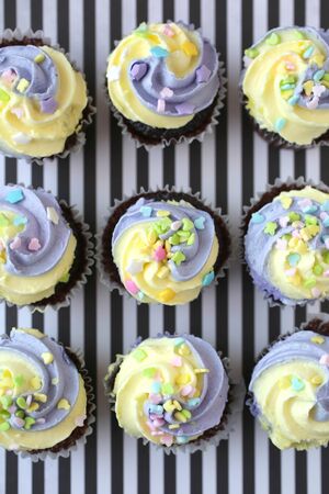Top view of nine yellow and lilac cupcake on a black and white linedの写真素材