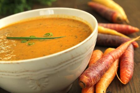 Close up of a vegetables soup with fresh carrots on a wooden tableの写真素材
