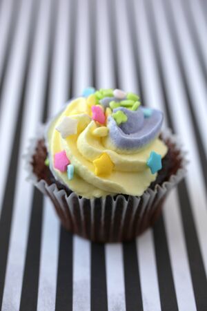 Yellow and lilac cupcake on a black and white linedの写真素材