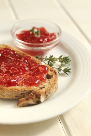 Wheat bread with homemade strawberry jam on a white plate on a whiteの写真素材
