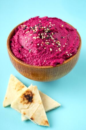 Delicious vegetarian beetroot hummus with pita pieces on pale blue backgroundの写真素材