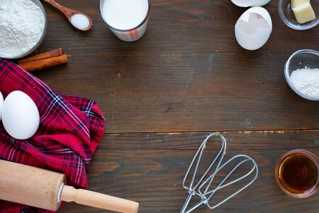 Ingredient for making delicious pancake ( eggs, flour, butter, milk with fresh maple syrup) on a red tablecloth and a rolling pinの写真素材