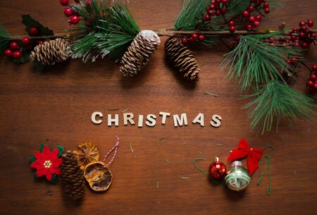Wooden pieces made Christmas word with pine trees and cones and christmas decoration itemsの写真素材