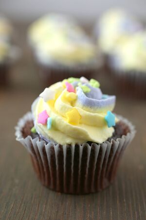 Easter yellow and lilac chocolate cupcake on a wooden backgroundの写真素材