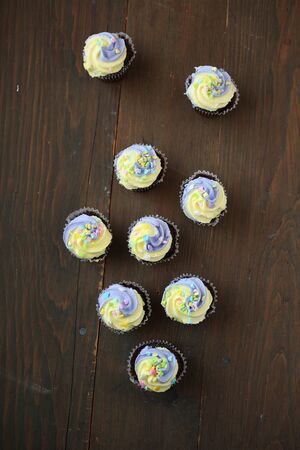 Top view of yellow and lilac cupcake on a black and wooden backgroundの写真素材