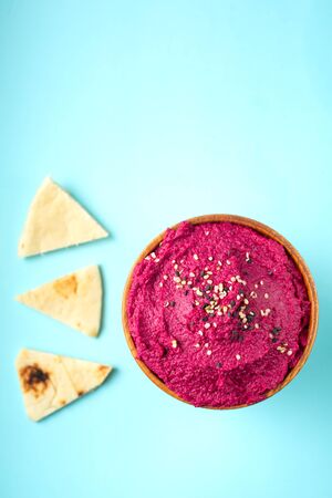 Delicious vegetarian beetroot hummus with three pita pieces on pale blue backgroundの写真素材