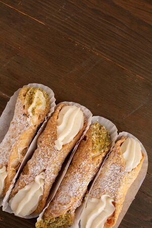 Top view of four cannoli freshly display in nice paper on a wooden backgroundの写真素材