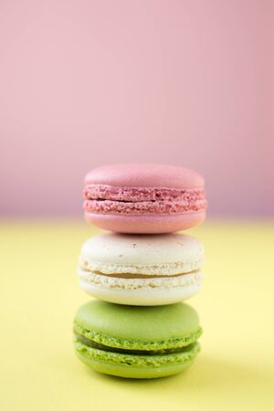 Pink, white and green traditional french macaroons on pink and yellow backgroundの写真素材