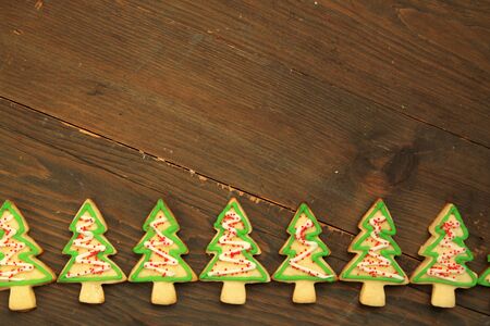 Row of christmas tree cookies with icing on a wooden table backgroundの写真素材