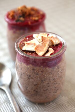 Healthy chocolate chia pudding with berry coulis on top and coconut on a wooden backgroundの写真素材