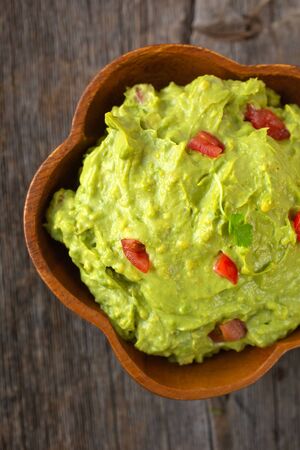 Top view of a bowl of traditional mexican guacamole on a wooden backgroundの写真素材