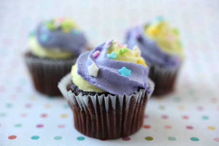 Easter yellow and lilac chocolate cupcake with candies on a colorful polka dotsの写真素材