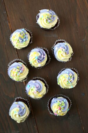 Top view of easter yellow and lilac chocolate cupcake on a wooden backgroundの写真素材