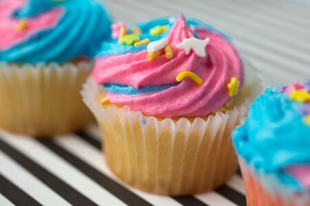 Cupcakes with blue and pink icing on a black and white lined backgroundの写真素材