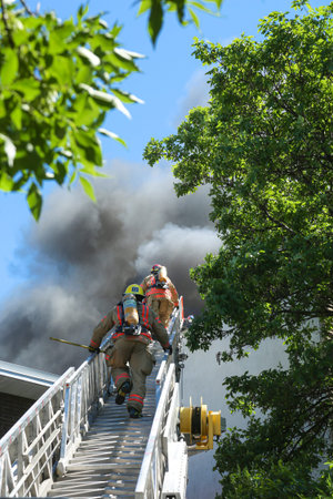 MONTREAL, CANADA - JUNE 18, 2020:  Firefighters climb skywards to tackle a blaze in a residential...