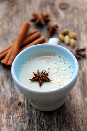 Blue cup with chai tea with cinnamon, anise and cardamom on a rustic wooden backgroundの写真素材