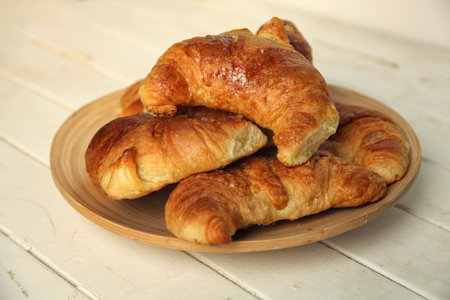 Fresh homemade croissant in a bamboo plate on a white backgroundの写真素材