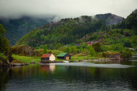 Low cloud clinging to the mountainside in the fjord over colorful houses and garages near Bergen in Norwayの写真素材